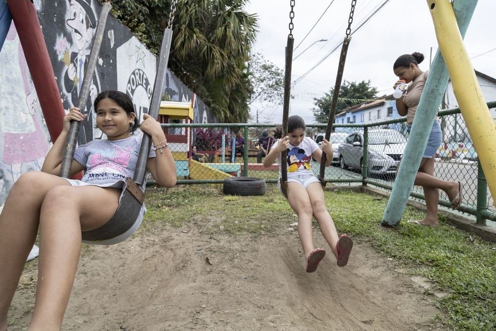 Menina se balançando num balanço de pneu, no parquinho construído no mutirão.