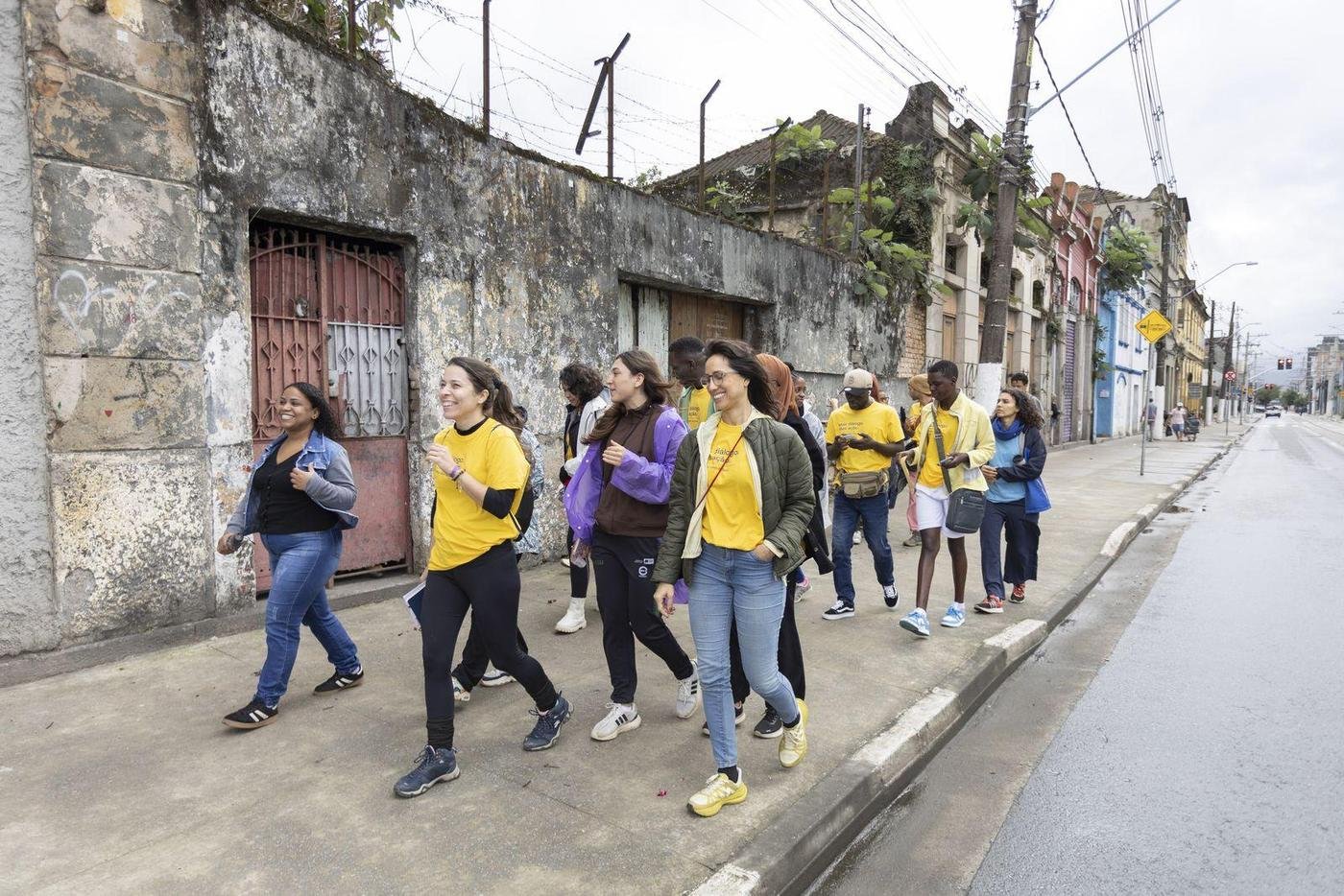 Grupo caminhando pela rua do bairro, olhando as casas e as fachadas.