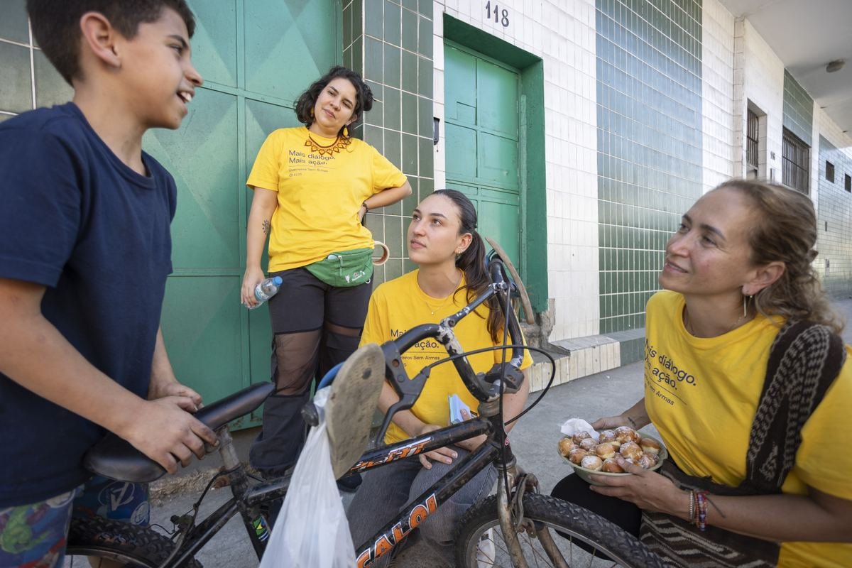 Participantes conversando com um menino e uma moradora na porta de casa, durante a escuta.
