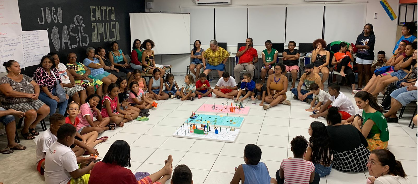 Grupo de pessoas reunidas em torno da maquete dos projetos coletivos sonhados pela comunidade